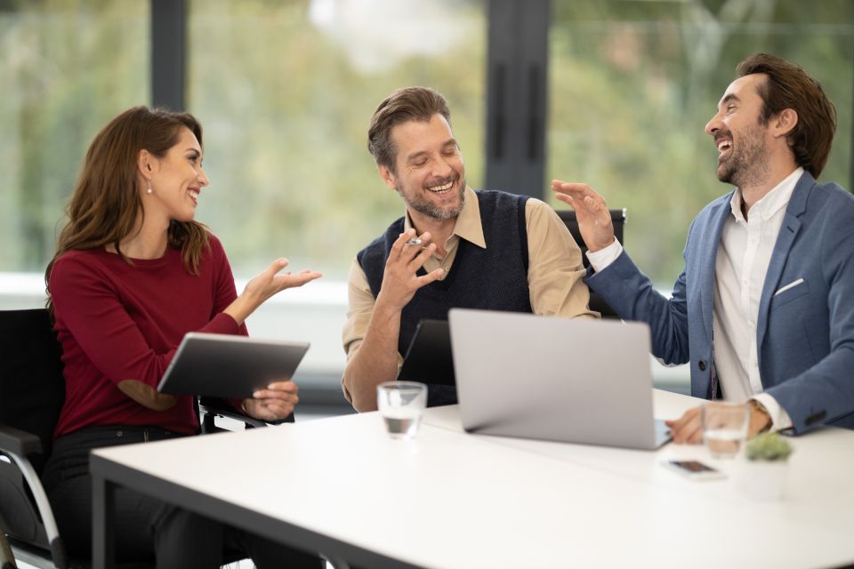 Tres profesionales conversando y revisando información en una mesa de trabajo luminosa